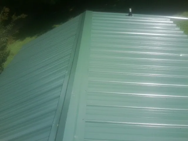 New green metal panels meeting at the ridge of a roof — Flat Roof Repair work by our crew in Big Pool