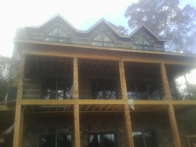 Dormers and porch framing on a large log home under construction — Roof Coating work by our crew in Big Pool