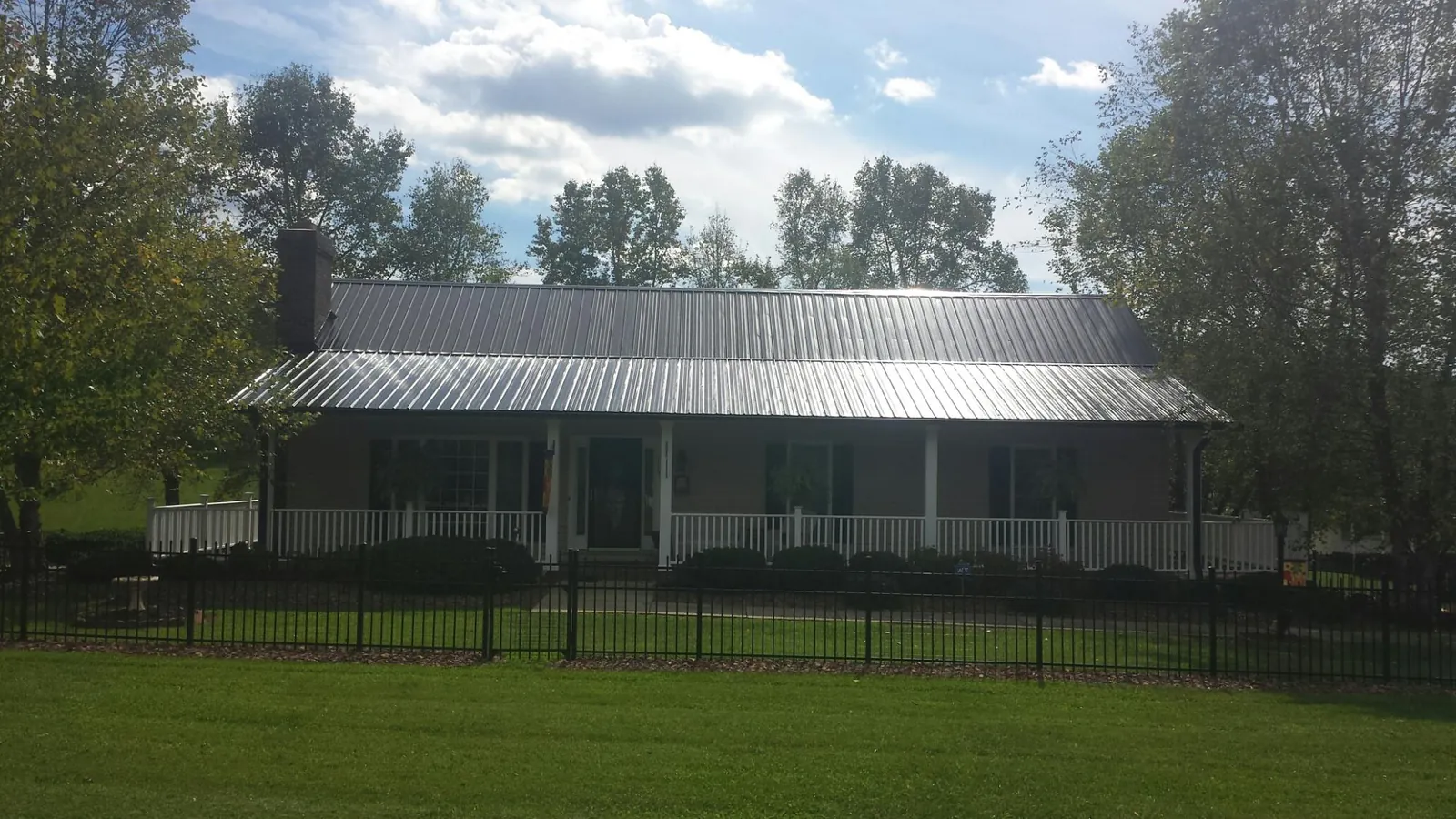 Gray metal roof on a brick ranch with a full width front porch — Gutter Guard Installation work by our crew in Big Pool