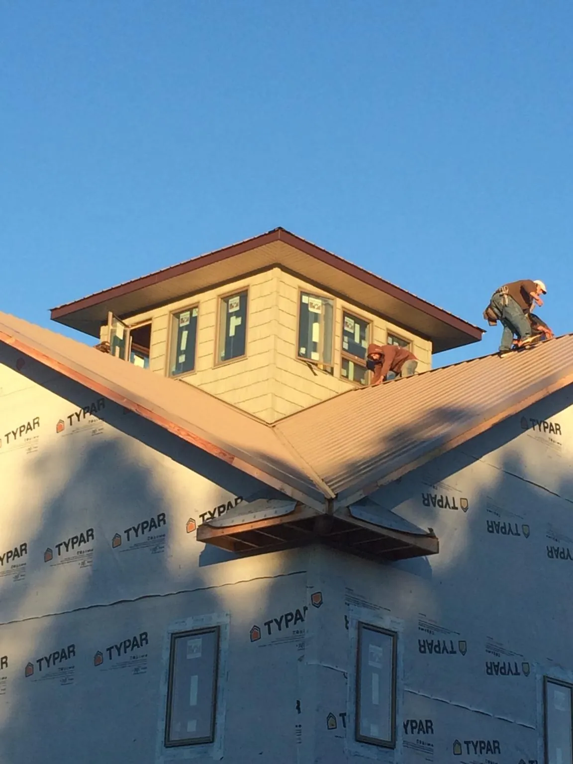 Roofers working around a rooftop cupola on a new metal roof at sunset — Roof Waterproofing in Big Pool by Roofing Brothers